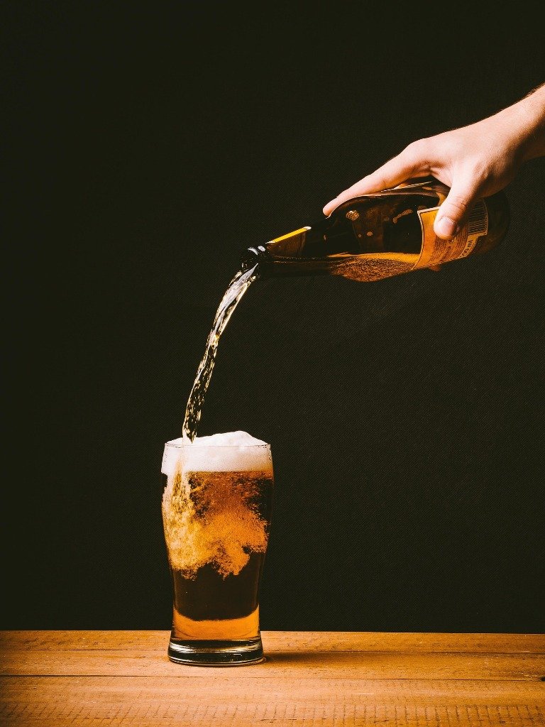 Rich Stout pouring from bottle into glass with dense foam